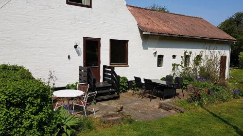 a white house with chairs and a table in front of it at Sænehus Husmandssted in Allinge