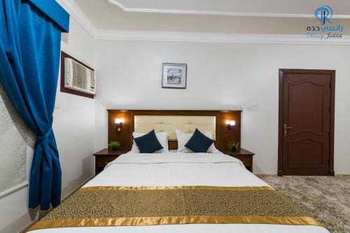 a bedroom with a large bed with blue curtains at Rancy Jeddah Aparthotel in Jeddah