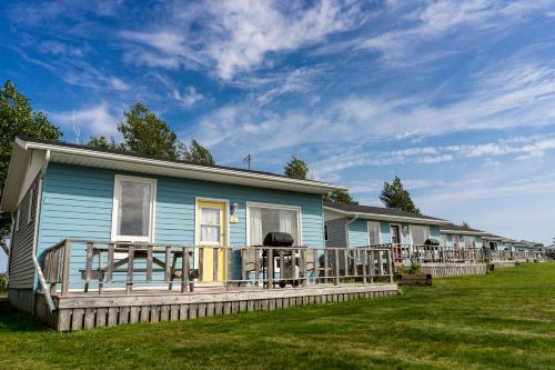 a blue house with a large deck on a yard at Sundance Cottages in Cavendish