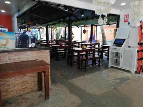 un restaurante con mesas y sillas de madera y ventanas en Rocky Cay Lodging en San Andrés