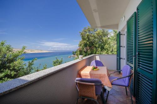 un tavolo e sedie su un balcone con vista sull'acqua di Apartments By the sea in Lopar a Lopar