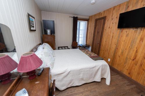 a bedroom with a bed with two lamps and a tv at Auberge Le Four à Pain in Petite-Rivière-Saint-François