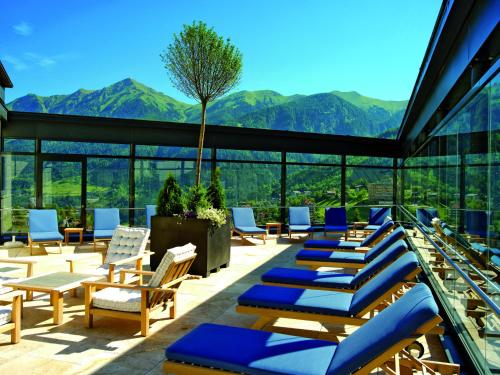a patio with lounge chairs and mountains in the background at Hotel Salzburger Hof in Bad Gastein