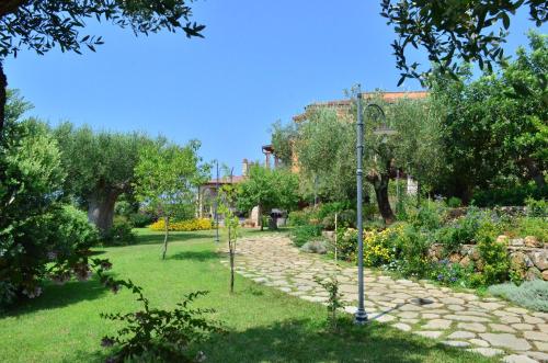 a garden with a stone path and trees and a building at Hotel Relais Pian delle Starze in Marina di Camerota