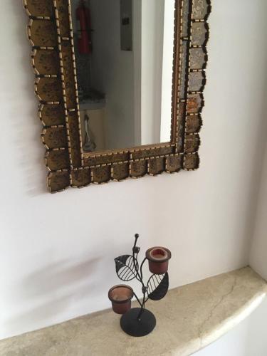a mirror on a wall with a vase on a shelf at Suites Parque Real in Quito
