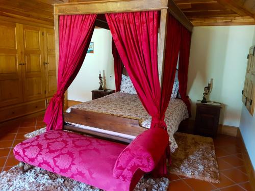 a bedroom with a canopy bed with red curtains at Quinta Da Penela in Vieira do Minho