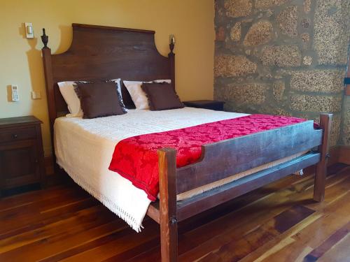 a bedroom with a large bed with a wooden headboard at Quinta Da Penela in Vieira do Minho