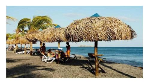 a group of people sitting under a straw umbrella on a beach at Playa Blanca in Playa Blanca