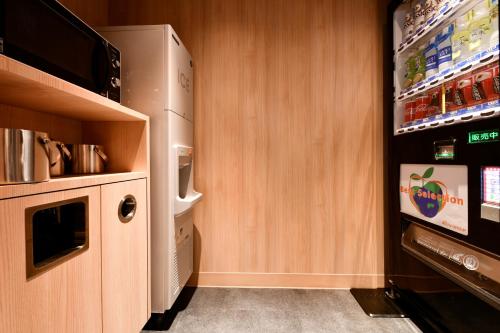 a small kitchen with a refrigerator and a microwave at Vessel Hotel Campana Susukino in Sapporo