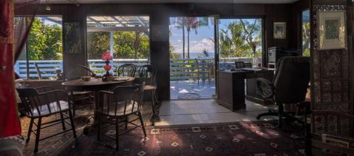 a room with a table and chairs and a balcony at Ma'ukele Lodge in Pahoa