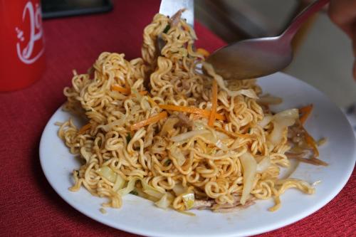 a plate of noodles with a spoon on a table at Tropical Valley Homestay - Villas in Phong Nha