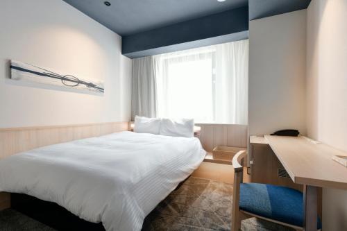 a bedroom with a bed and a desk and a window at Vessel Hotel Campana Susukino in Sapporo