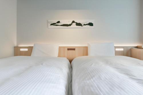 two white beds sitting next to each other in a bedroom at Vessel Hotel Campana Susukino in Sapporo