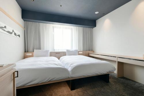 a bedroom with two beds and a window at Vessel Hotel Campana Susukino in Sapporo