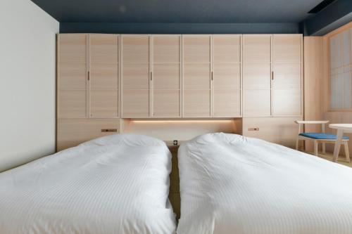 two white beds in a bedroom with cabinets at Vessel Hotel Campana Susukino in Sapporo