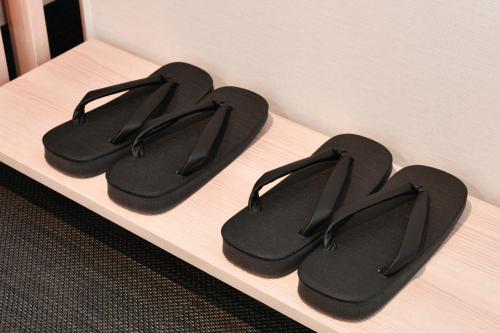 three pairs of black flip flops sitting on a shelf at Vessel Hotel Campana Susukino in Sapporo
