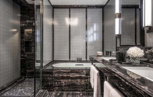 a bathroom with a tub and a glass shower at Four Seasons Hotel Kuala Lumpur in Kuala Lumpur
