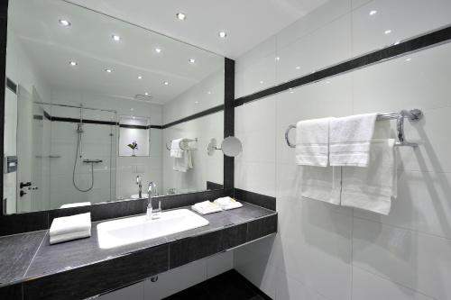Baño blanco con lavabo y espejo en Hotel Restaurant Höttche, en Dormagen