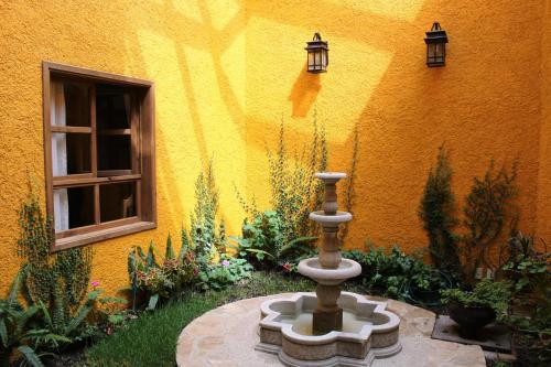 ogród z fontanną przed żółtym budynkiem w obiekcie Hotel San Jose w mieście San Cristóbal de Las Casas