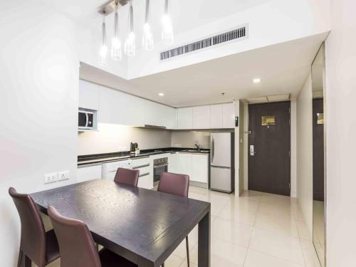 a kitchen with a wooden table and chairs in a room at Maitria Hotel Sukhumvit 18 Bangkok – A Chatrium Collection in Bangkok