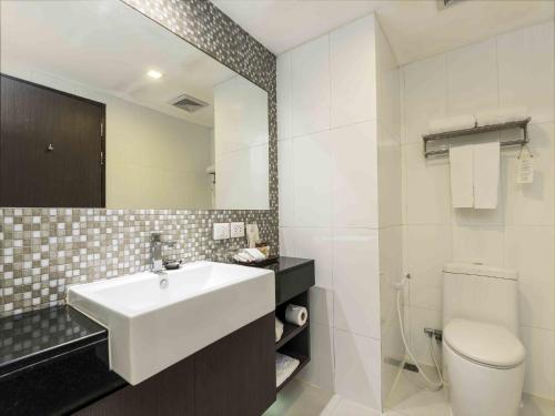 a bathroom with a sink and a toilet and a mirror at Maitria Hotel Sukhumvit 18 Bangkok – A Chatrium Collection in Bangkok