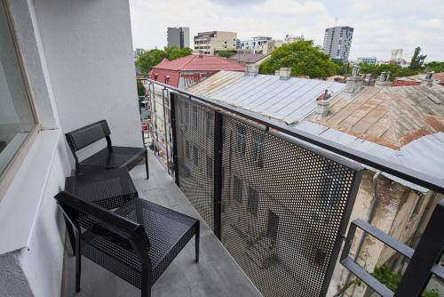 a balcony with two chairs and a view of a city at AT Central Apartments in Bucharest