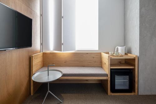 a room with a bench with a table and a tv at TSUGU Kyoto Sanjo by THE SHARE HOTELS in Kyoto