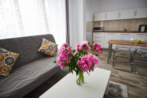 a vase of pink flowers on a table in a living room at AT Central Apartments in Bucharest
