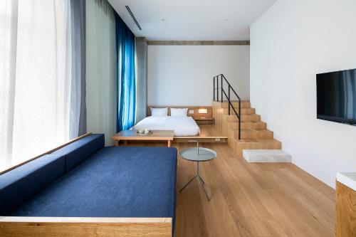a bedroom with a blue couch and a bed at TSUGU Kyoto Sanjo by THE SHARE HOTELS in Kyoto