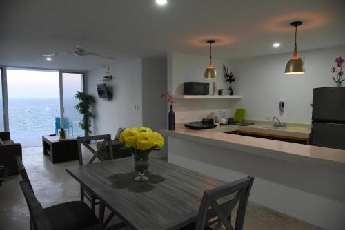 a kitchen and dining room with a table with yellow flowers on it at Torre Aguamarina in Campeche