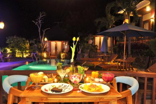a wooden table with plates of food on it next to a pool at Ocean Terrace Suite And Spa Luxury in Nusa Penida