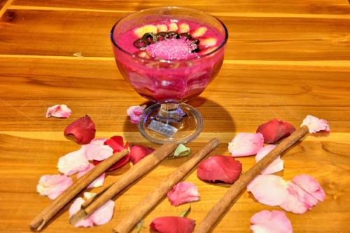 a table with a glass of pink drink and some flowers at Ocean Terrace Suite And Spa Luxury in Nusa Penida