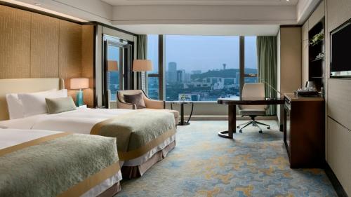 a hotel room with two beds and a desk and a window at Kempinski Hotel Xiamen in Xiamen