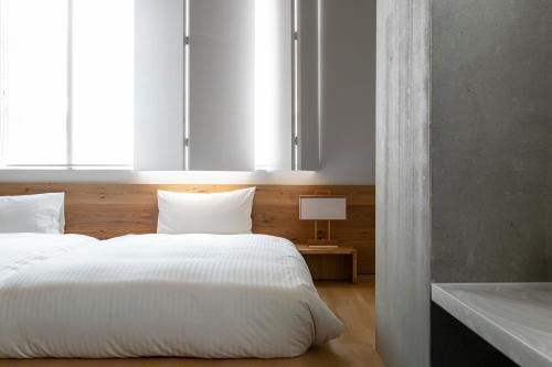 a bedroom with a large white bed and a window at TSUGU Kyoto Sanjo by THE SHARE HOTELS in Kyoto