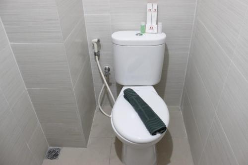 a bathroom with a toilet with a green towel on it at Compact Studio Room at Gateway Pasteur Apartment near Exit Toll By Travelio in Bandung