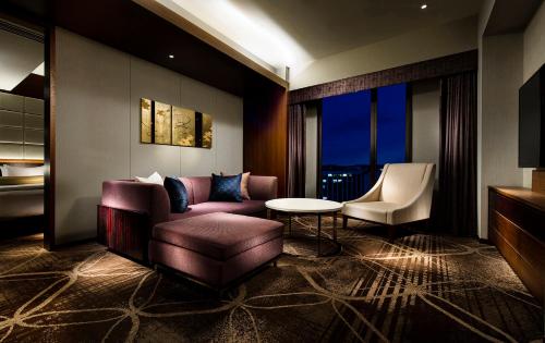 a living room with a couch and a chair and a table at RIHGA Royal Hotel Kyoto in Kyoto