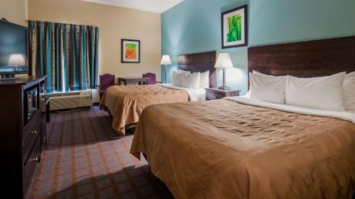 a hotel room with two beds and a flat screen tv at Red Lion Inn & Suites Blue Springs in Blue Springs