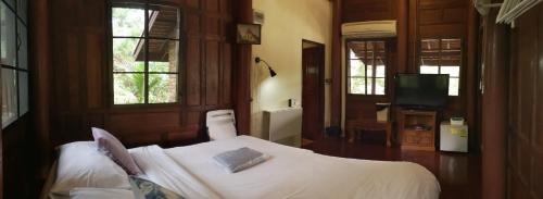 a bedroom with a bed and a tv and windows at Ayodhara Village in Phra Nakhon Si Ayutthaya