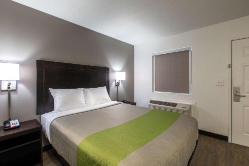 1 dormitorio con 1 cama grande con manta verde en Studio 6-Greenville, SC - I-85 Near Downtown, en Greenville