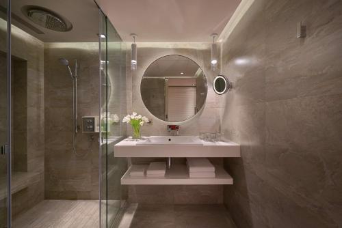 a bathroom with a tub, sink and mirror at Grand Hyatt Taipei in Taipei