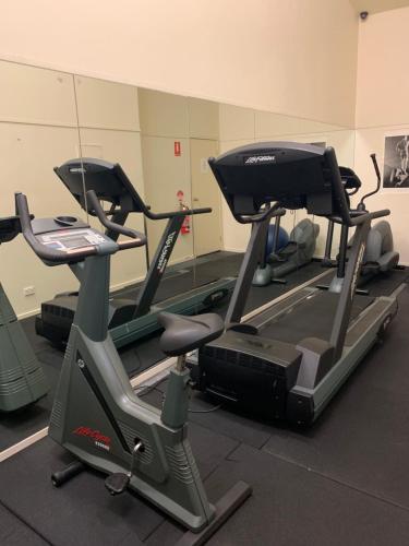 a gym with three tread machines in a room at Cosy City Apartment in Melbourne
