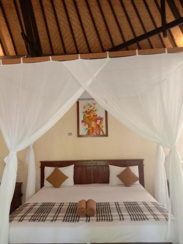 a bedroom with a bed with two shoes on it at Bali Gecko Homestay in Pemuteran