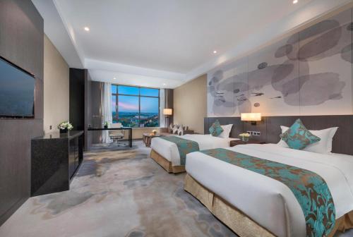 a hotel room with two beds and a flat screen tv at Shenyang Huaqiang Novlion Hotel in Daoyi