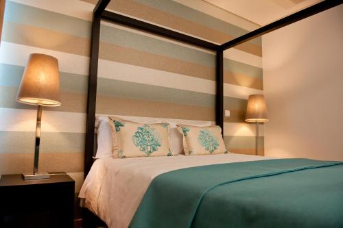 a bedroom with a bed with a striped wall at Atlantida Mar Hotel in Praia da Vitória