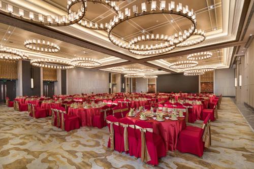 a large banquet hall with red tables and chandeliers at Shenyang Huaqiang Novlion Hotel in Daoyi