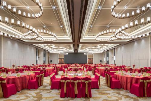 a large banquet hall with red tables and chandeliers at Shenyang Huaqiang Novlion Hotel in Daoyi