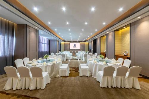 a banquet hall with white tables and chairs and a screen at Shenyang Huaqiang Novlion Hotel in Daoyi