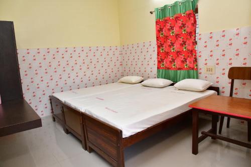 a small bed in a room with a red curtain at Hotel Ganesh Lodge in Kanyakumari