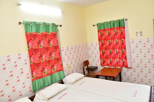 a room with two beds and red curtains at Hotel Ganesh Lodge in Kanyakumari
