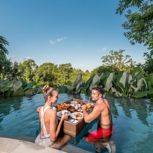 a man and woman eating food in the water at tanadewa Resort Ubud Bali by Cross Collection in Ubud